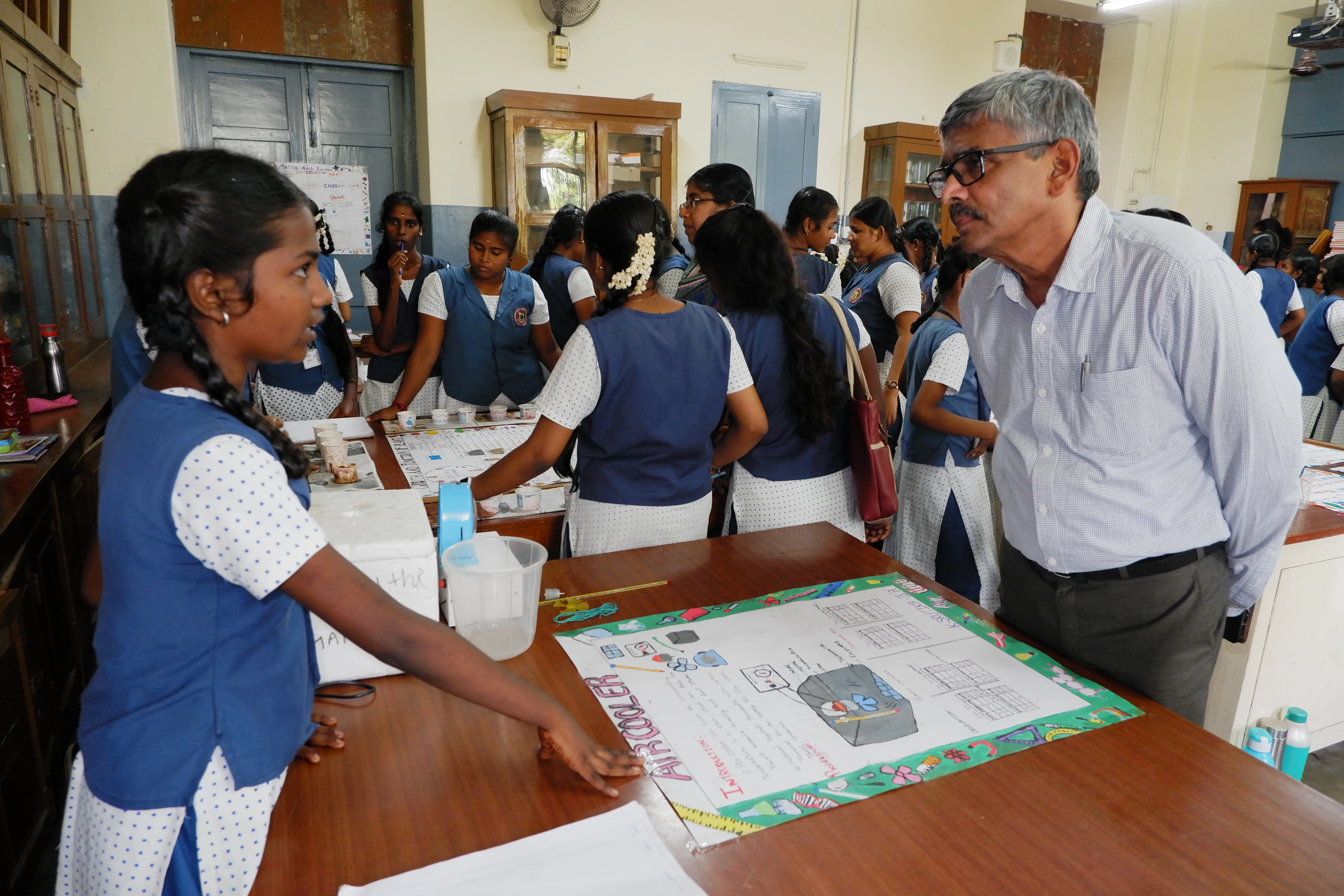 A KSICT trustee visiting students presenting their science project at a partner school